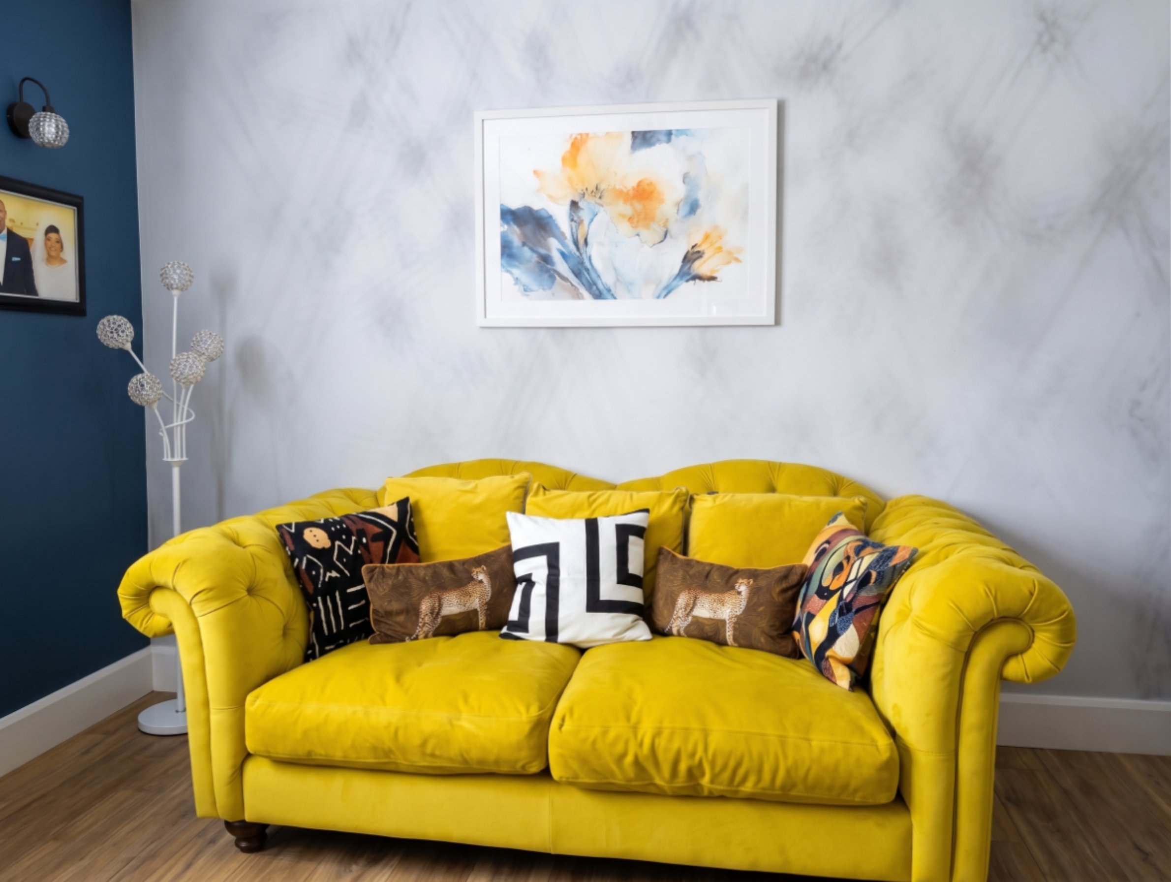 Yellow Chesterfield sofa with marble wall and watercolour art